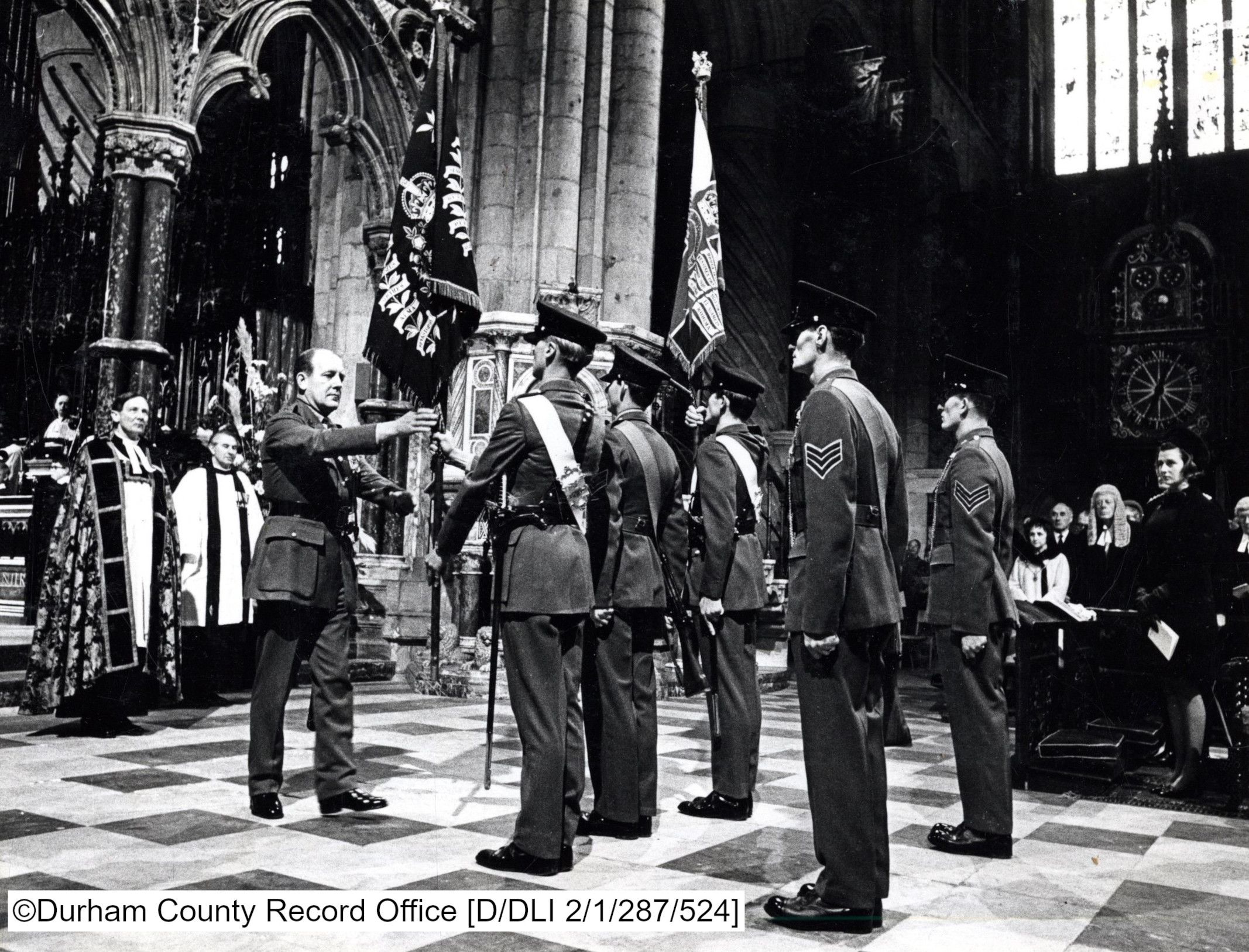 Soldiers of the DLI present some Colours to be laid up inside Durham Cathedral in this black and white photo.
