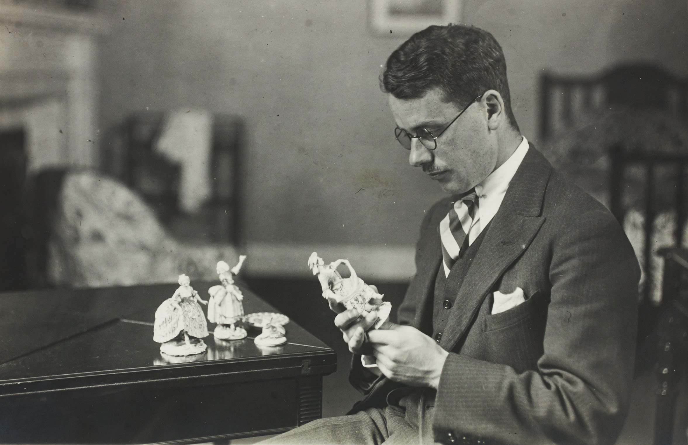 A young Malcolm MacDonald inspects a series of three ceramic figures