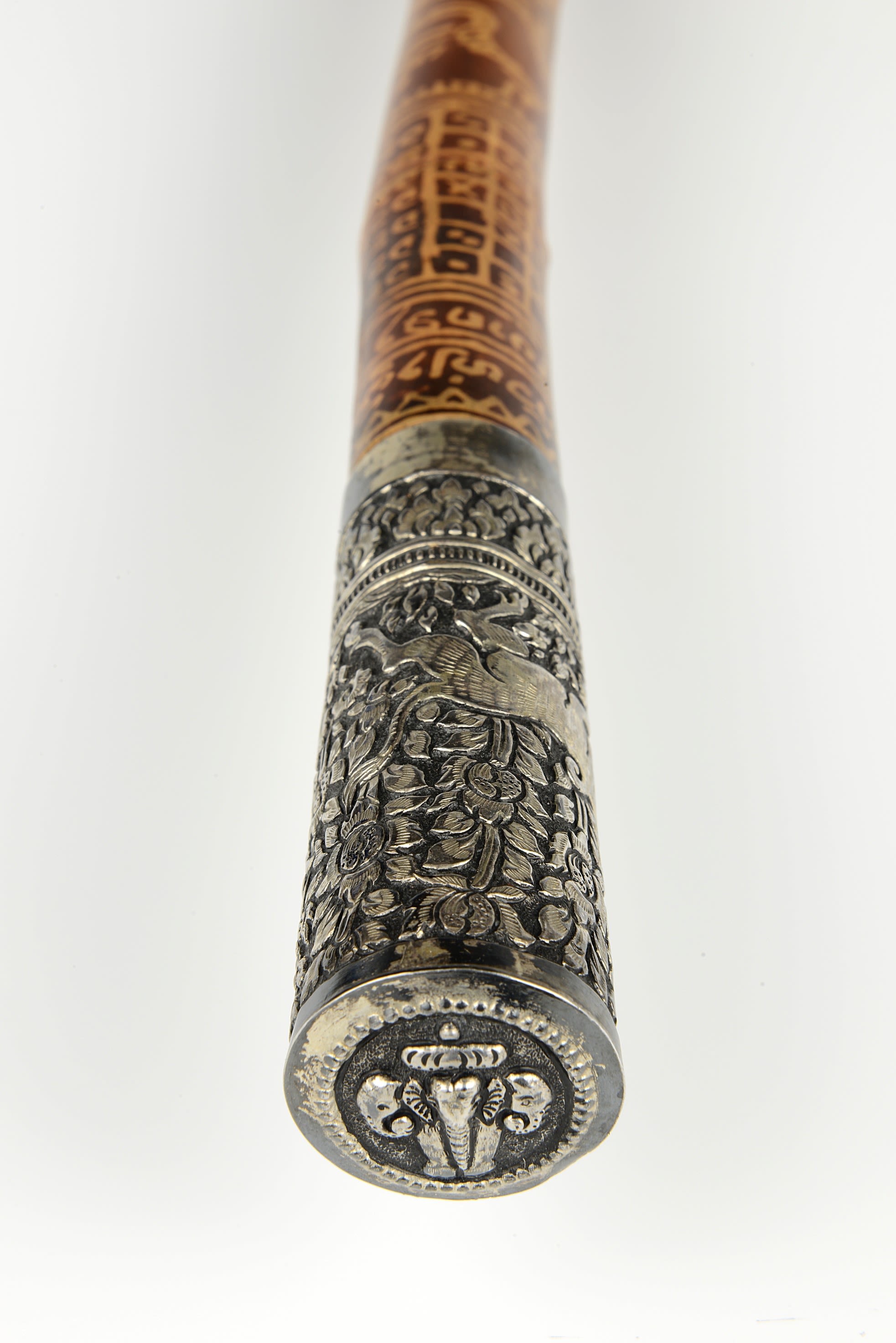 Expanded view of the baton, showing more of the carved metal patterns and the wooden tube it attaches to. The baton is patterned throughout.