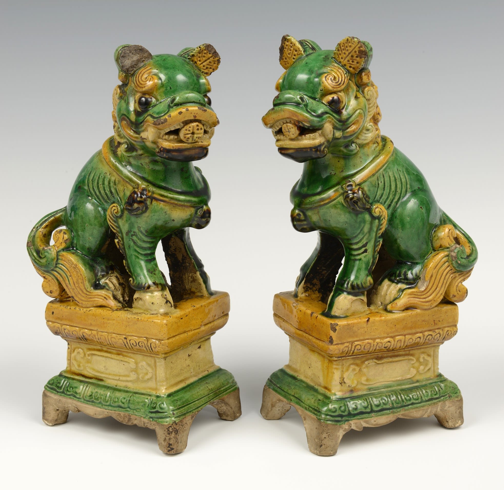 Two green and yellow figures shaped like lions, stood on small plinths