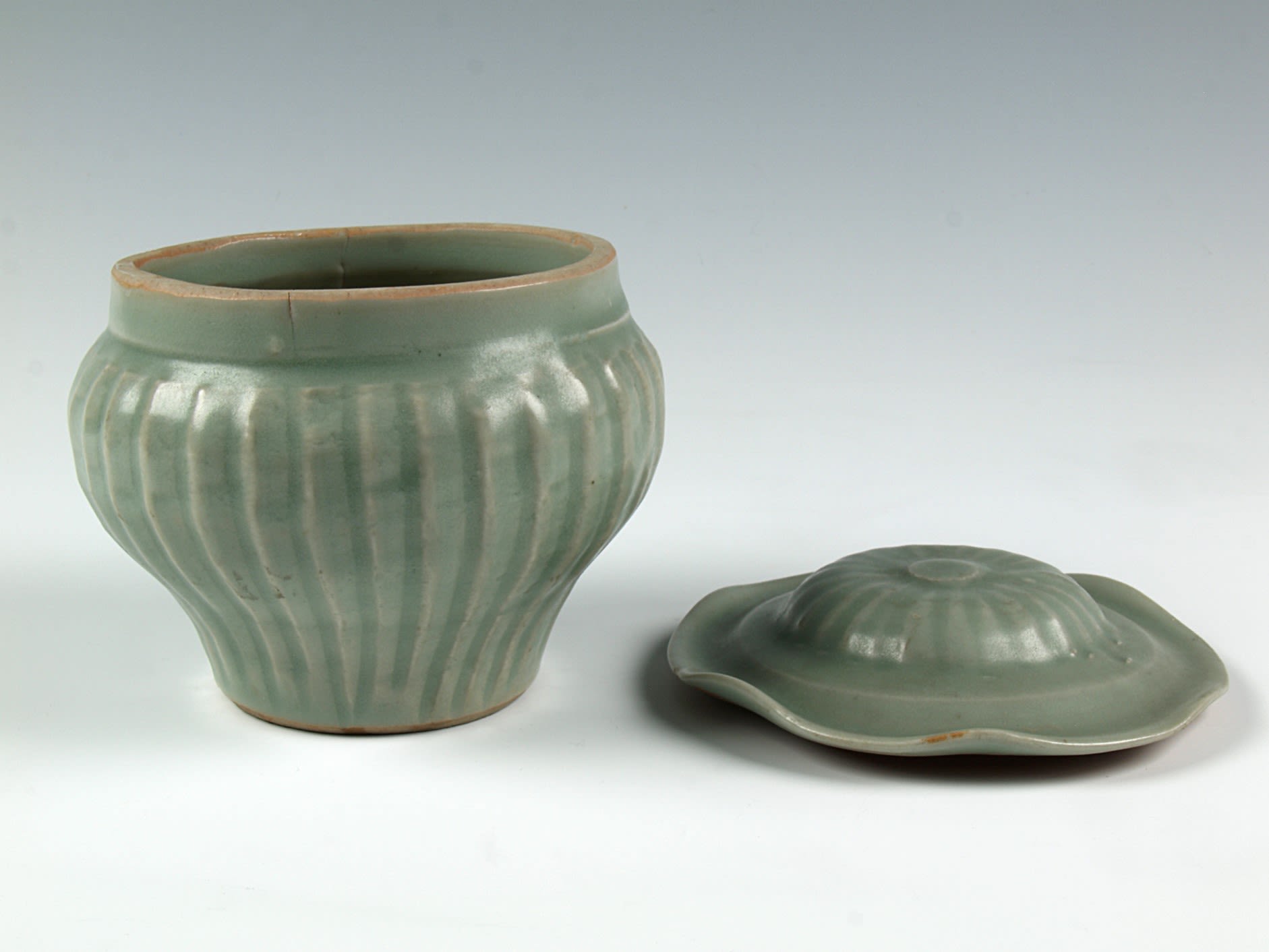 A jar in two parts, the lid is separate from the base. Turquoise green colour with brownish textured stripes.