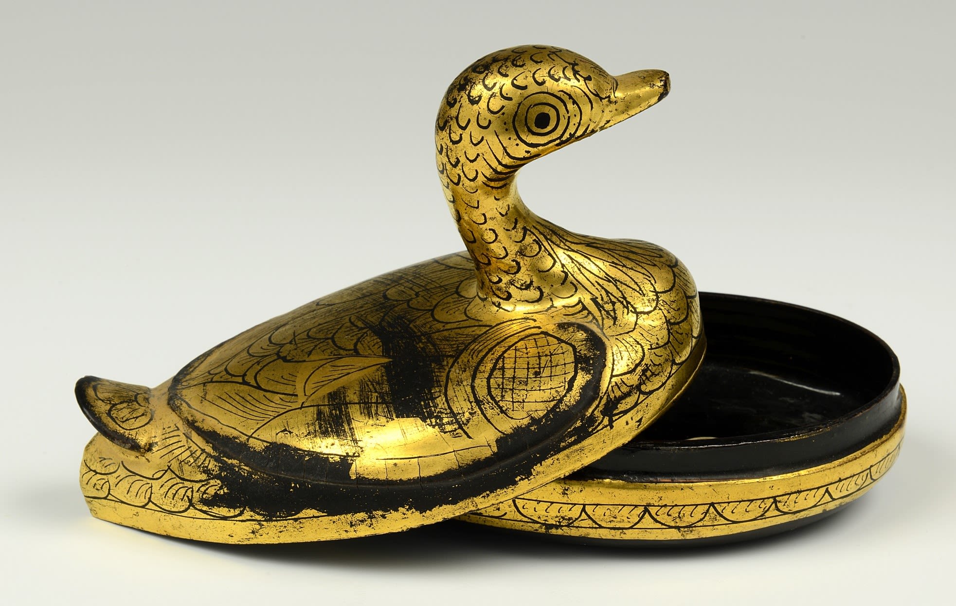 Box in two parts, resembling a duck. The box is golden on the outside, with a black interior.