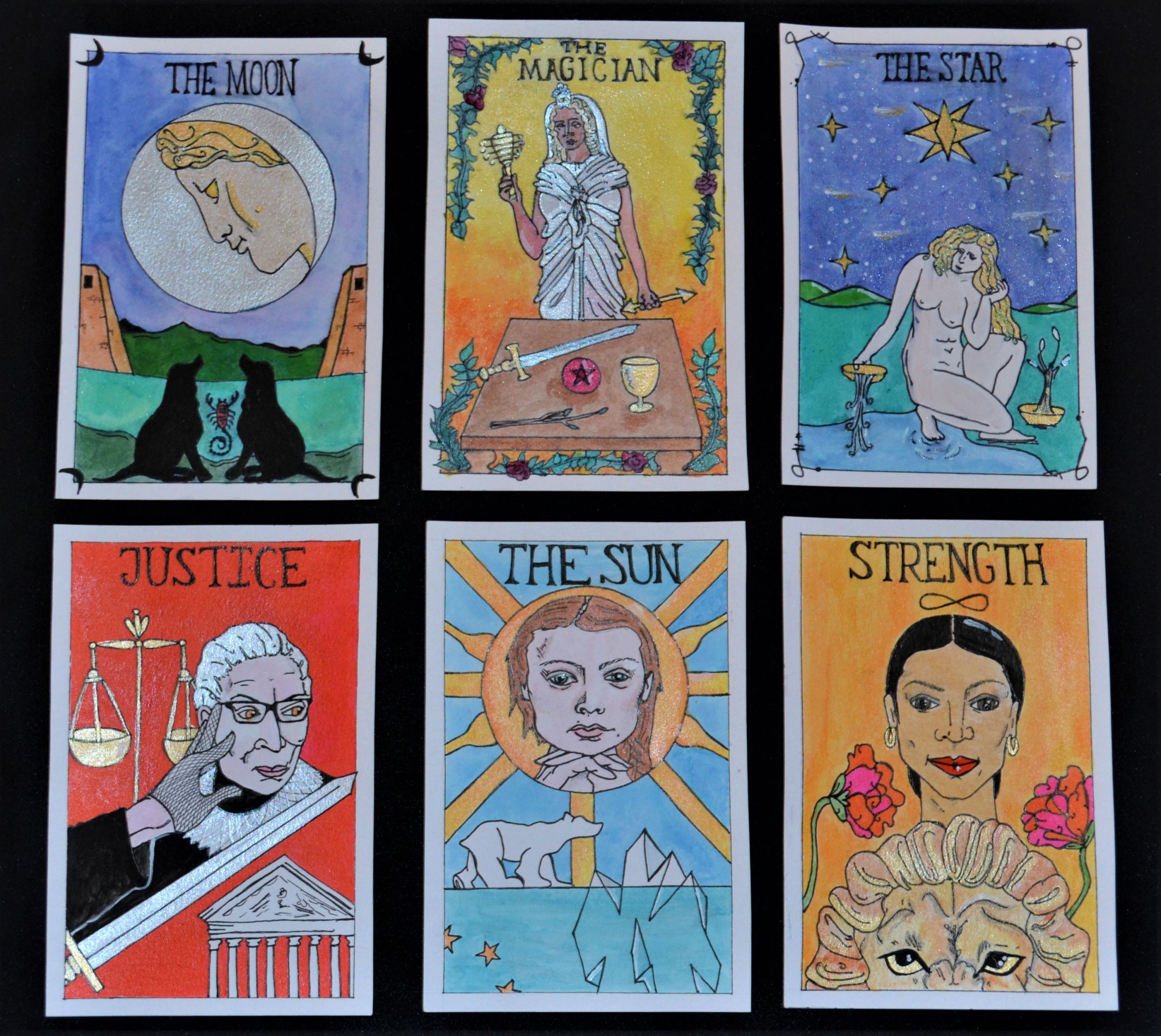 Group of six tarot cards depicting the goddess Selene as The Moon, the goddess Isis as The Magician, the goddess Aphrodite as The Star, Ruth Bader Ginsburg as Justice, Greta Thunberg as The Sun, and Alexandria Ocasio Cortez as Strength.