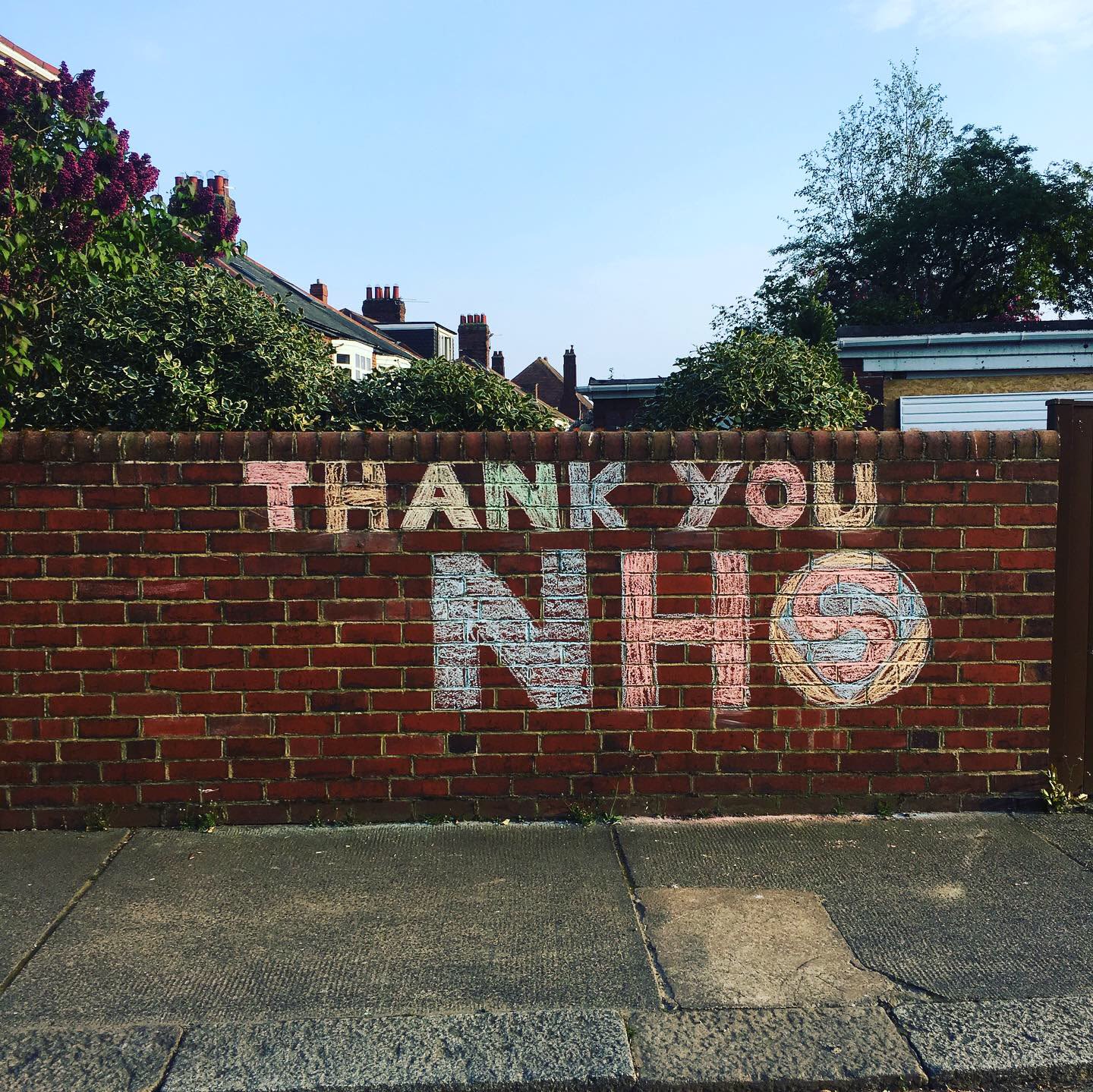 Chalk graffiti on brick wall which reads 'Thank You NHS'. The 'S' is in the style of superman