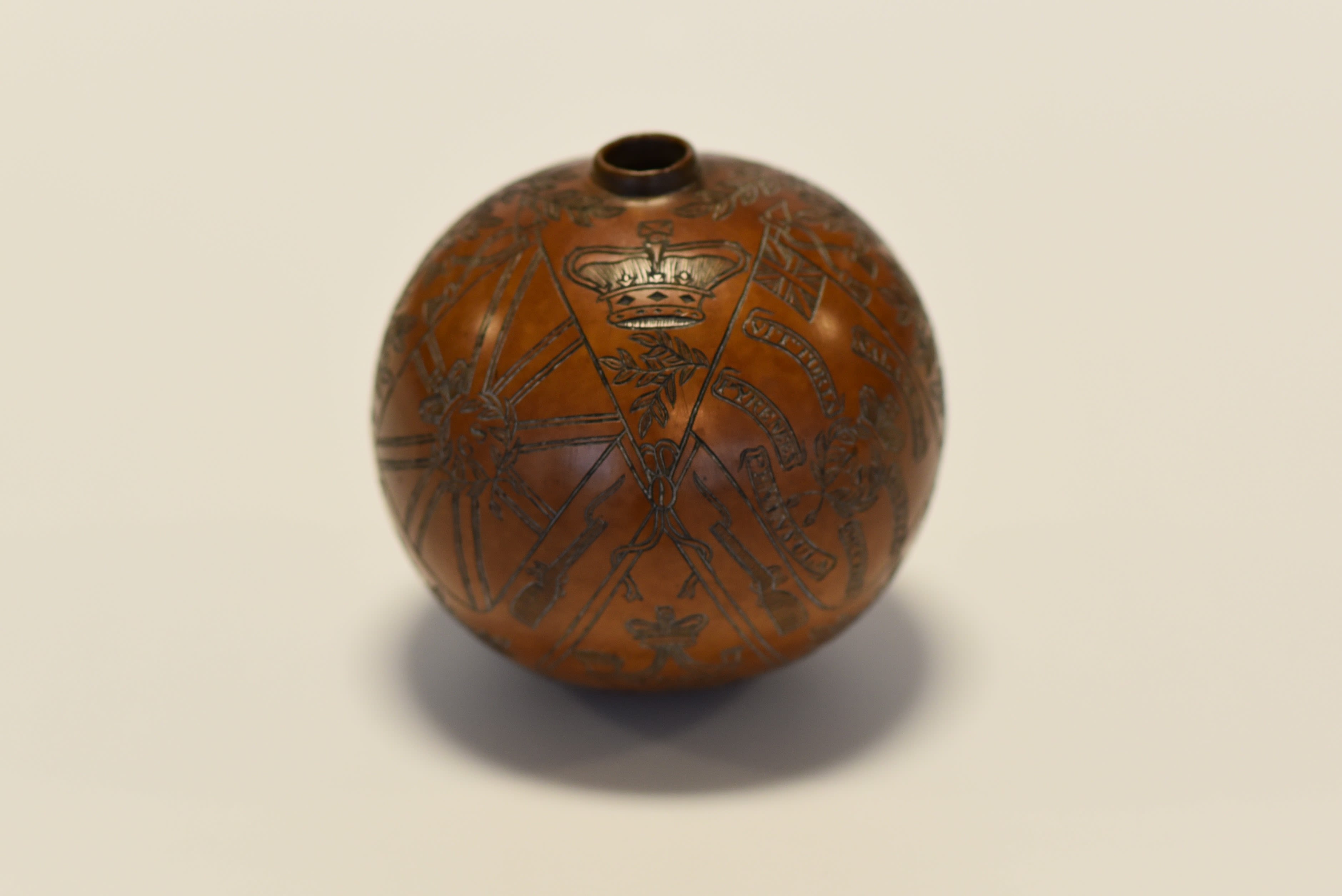 Brown circular vessel carved to show set of Colours with crossed poles.
